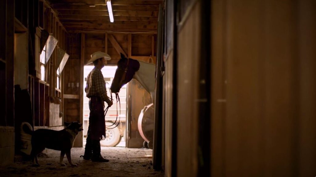 Rancher with horse and dog in barn